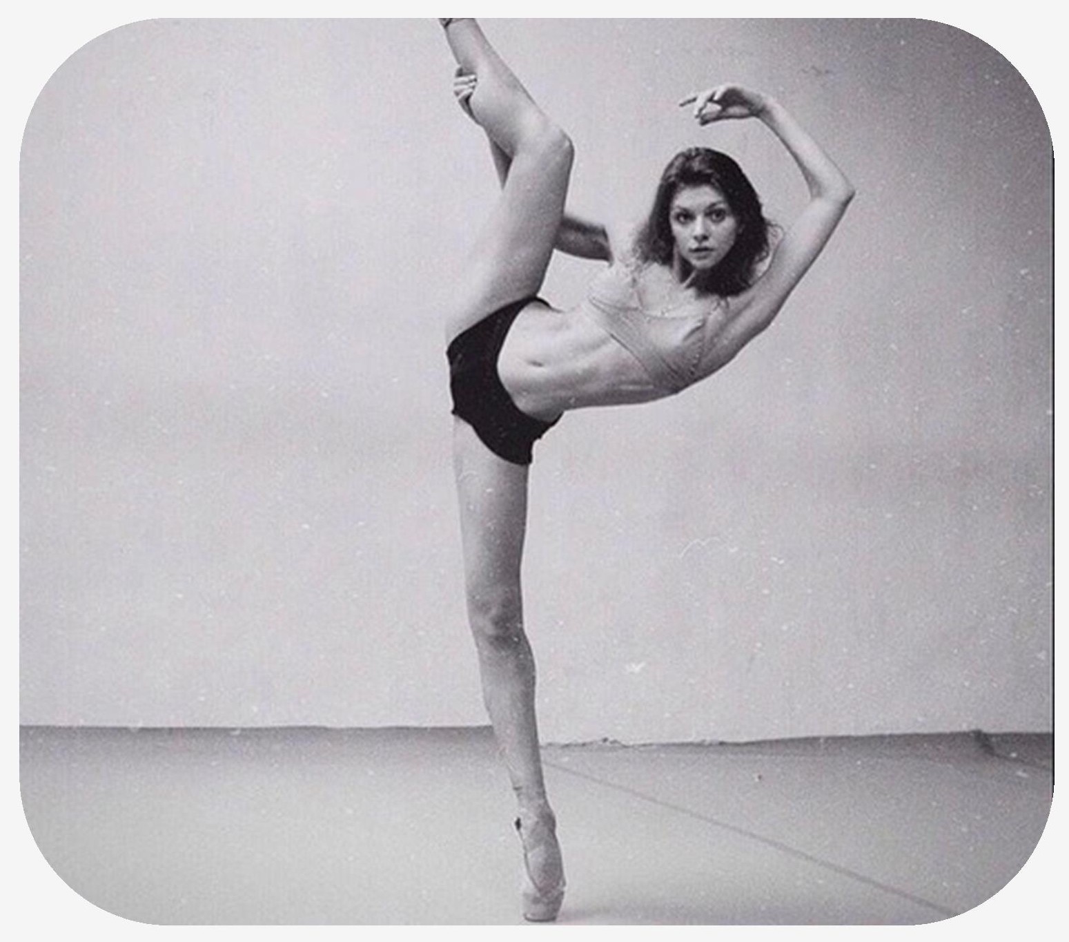 Female ballerina on toes of one foot while holding other foot in the air pointed up