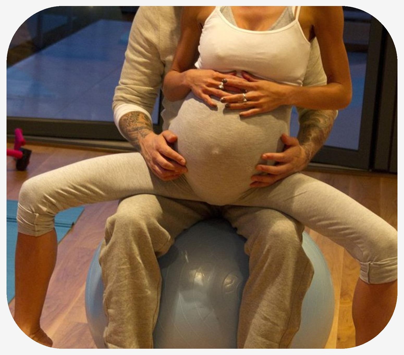 Pregnant woman sitting on an exercise ball on her husband lap