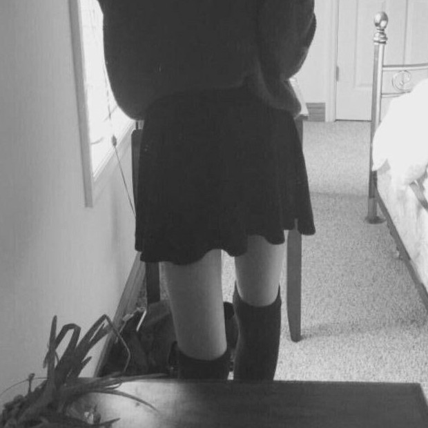 Front view of woman standing wearing a skirt and stockings.