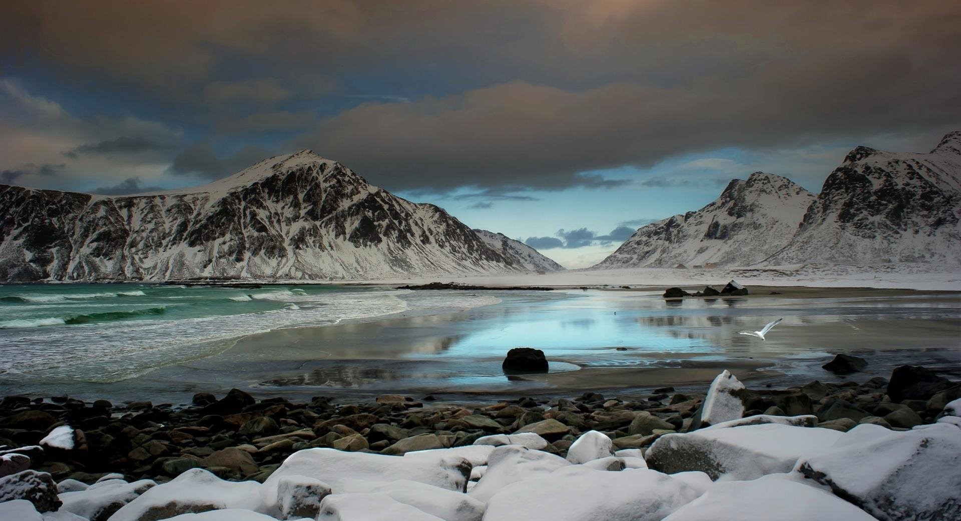 Snowy valley in the mountains surrounding an unfrozen arctic lake