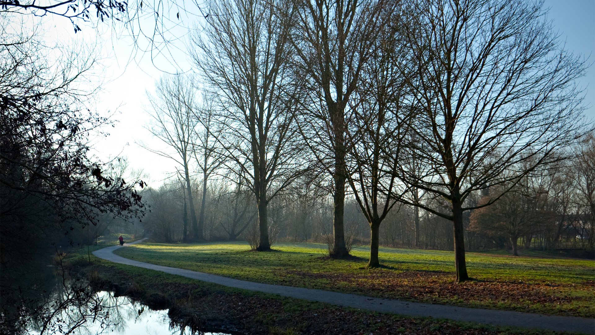 Long curving walkway along a river, with people walking in the distance