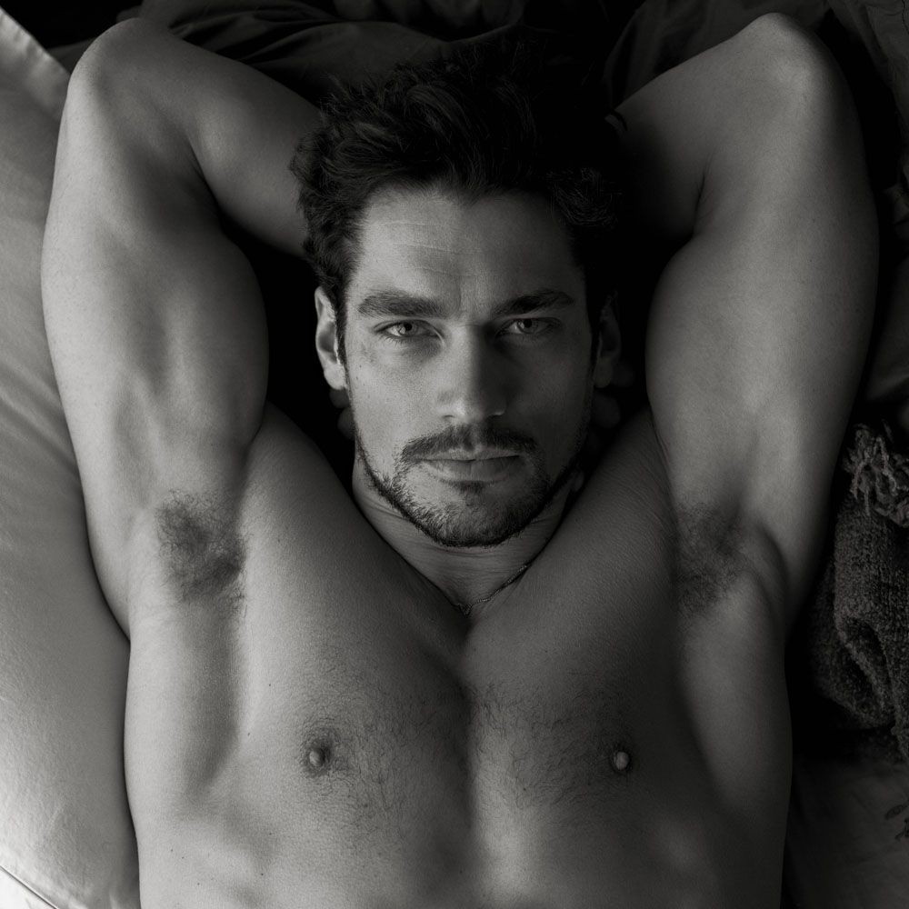 Muscular man laying on a bed with head laying on both hands