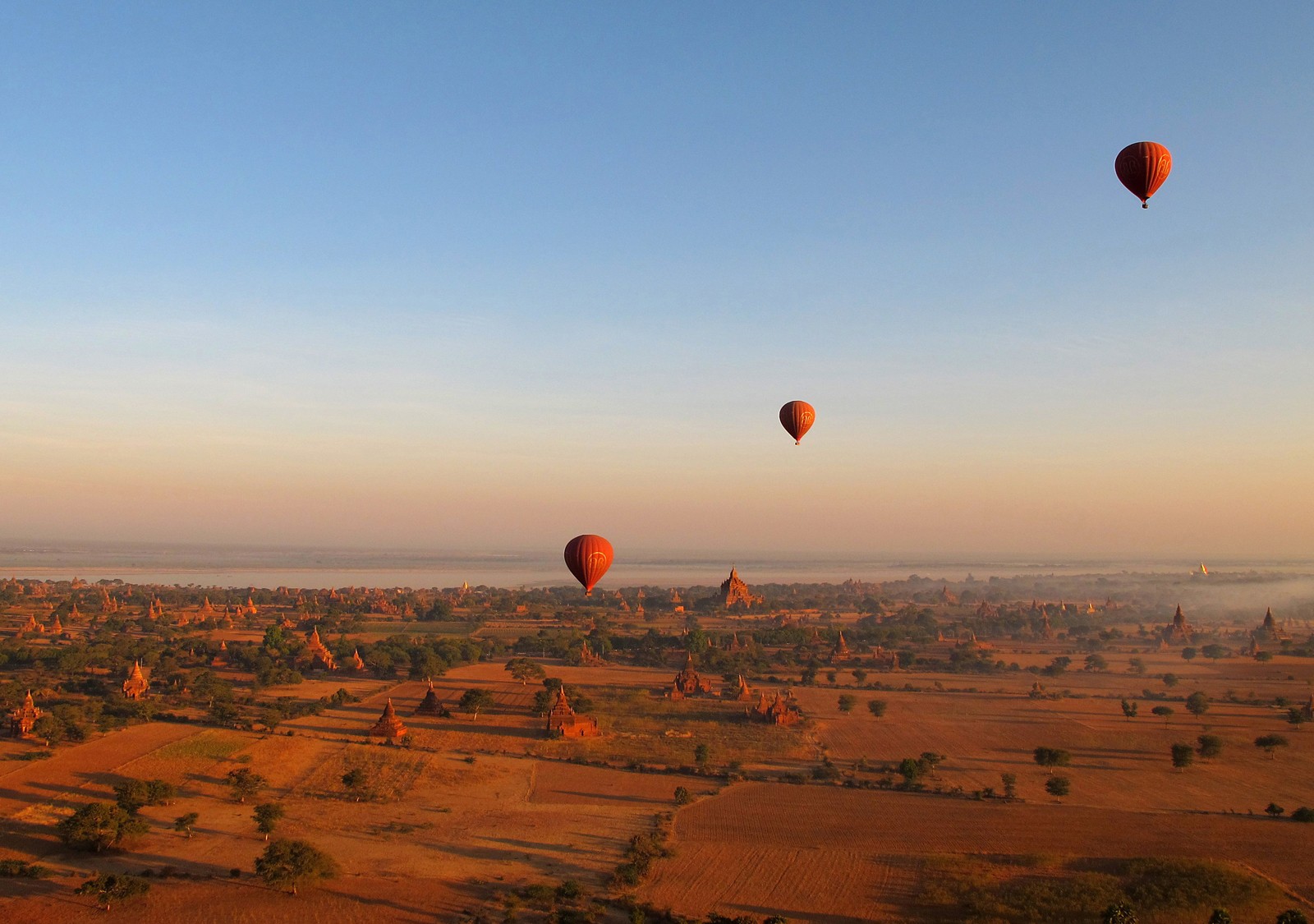 Muktiple hot air ballons in the air at different distances.
