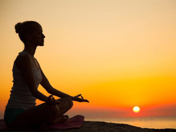 Woman meditating outside at sunset